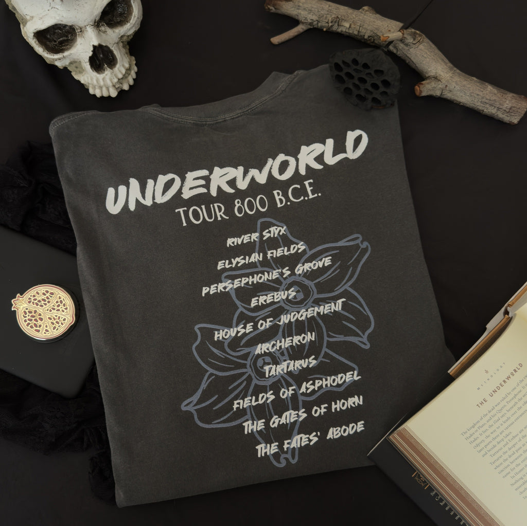 A dark charcoal gray t-shirt with white and light blue narcissus flower graphic with text reading 'UNDERWORLD TOUR 800 B.C.' and several underworld locations.